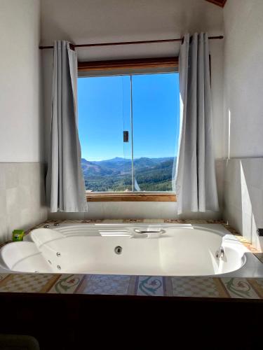 eine weiße Badewanne in einem Zimmer mit Fenster in der Unterkunft Chalés Nascer da Lua in Monte Verde
