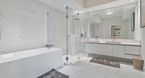 a white bathroom with a tub and a sink at Luxury Resort Beach Condo in Riviera Beach