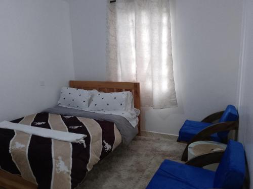 a bedroom with a bed and a window with blue chairs at Kiserian in Kitengela 
