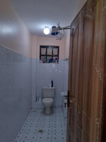 a bathroom with a toilet and a window and a light at Kiserian in Kitengela 
