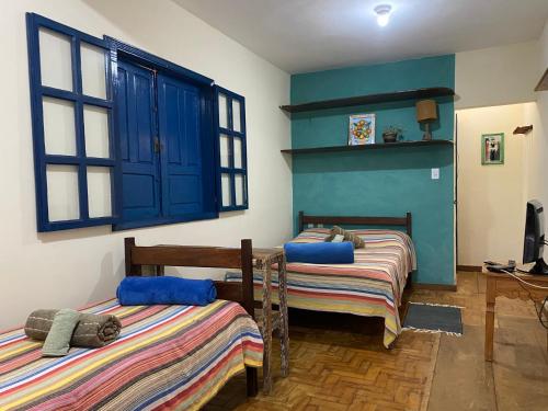 two beds in a room with blue walls and windows at Pousada Pico do Papagaio in Aiuruoca