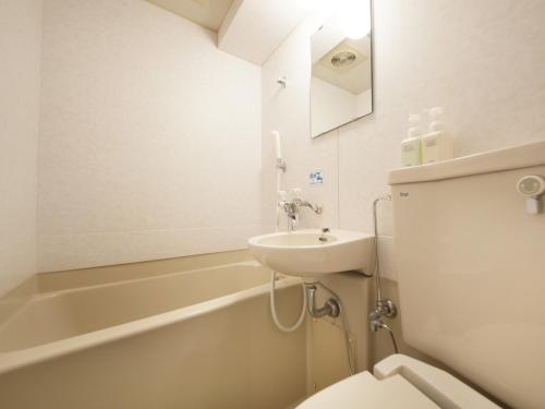 a bathroom with a sink and a toilet and a bath tub at Hotel Green Arbor in Sendai