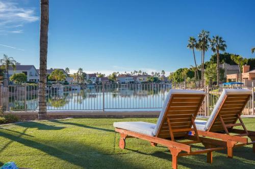 two chairs sitting on the grass near a body of water at Lakeside Luxury Val Vista in Gilbert