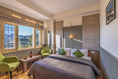 a bedroom with a bed and two green chairs at Shiwalik Hills in Shimla