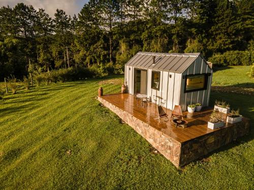 a tiny house on a deck in a field at Tiny House - Rancho Queimado SC - 15 Min do centro in Rancho Queimado