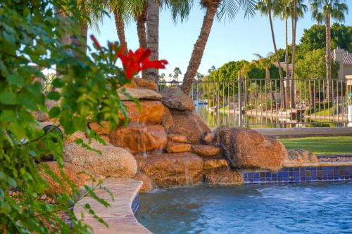 a rock fountain in a pool with a red flower at Lakeside Luxury Val Vista in Gilbert