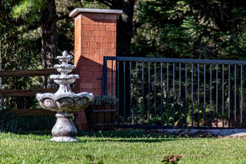 a fountain in the grass next to a fence at Tiny House - Rancho Queimado SC - 15 Min do centro in Rancho Queimado