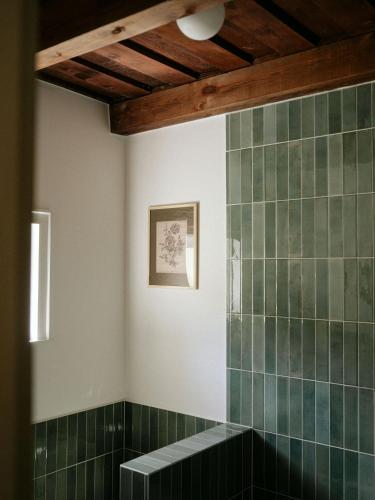 a bathroom with green tiled walls and a bench at Cserháti Házikó in Alsótold