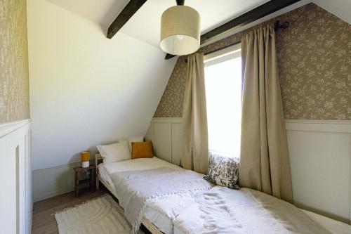 two beds in a room with a window at Cserháti Házikó in Alsótold
