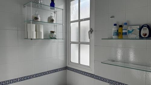a bathroom with a window and a white tiled wall at Casa Los Barberos in Valle de Abdalagís