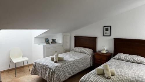 a bedroom with two twin beds and a chair at Casa Los Barberos in Valle de Abdalagís