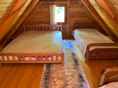 a bedroom with two beds in a log cabin at The Meridian in Valbonë