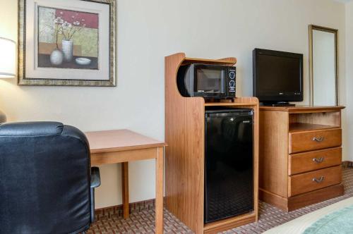 a hotel room with a television and a desk with a microwave at Super 8 by Wyndham Great Bend in Great Bend