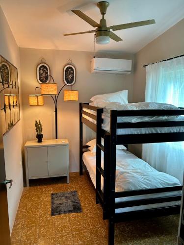 two bunk beds in a room with a ceiling fan at Isla Verde By The Beach Guest House in San Juan