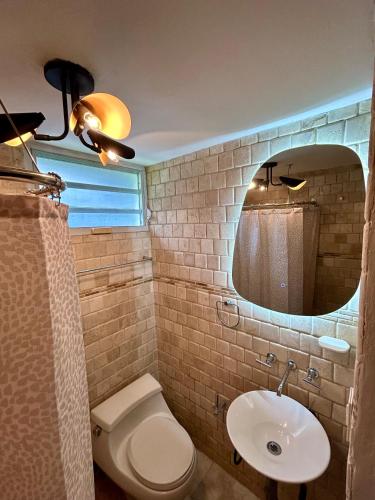 a bathroom with a toilet and a sink and a mirror at Isla Verde By The Beach Guest House in San Juan