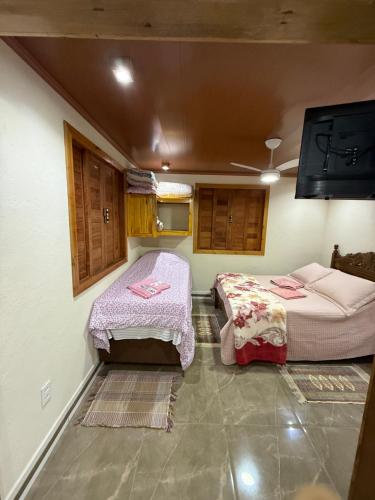 a room with two beds and a flat screen tv at Recanto Pin in Alfredo Chaves