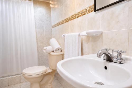 a white bathroom with a toilet and a sink at Casa Hotel Estancia Bogota in Bogotá