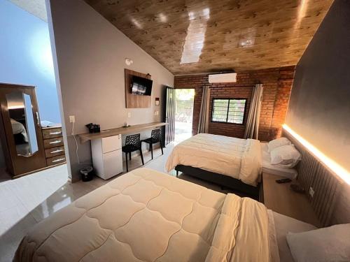 ein Schlafzimmer mit zwei Betten und einem Schreibtisch in der Unterkunft Hotel Suites Bambú in Minga Guazú