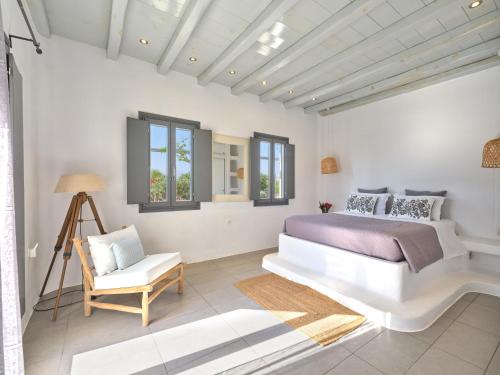 a bedroom with a bed and a chair and windows at SeaSalt Dream Villa,Santa Maria 5 min from Naousa in Santa Marina