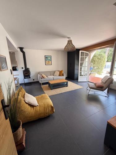 a living room with a couch and a table and a chair at Belle maison basco landaise avec jacuzzi in Labenne