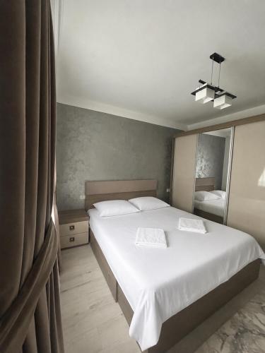 a bedroom with a large white bed and a mirror at Borșa ApartHotel 4 in Borşa
