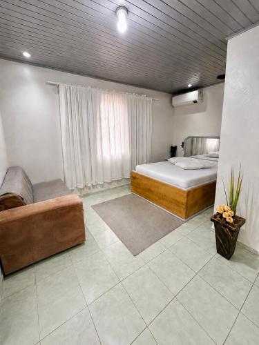 a large room with a bed and a couch at Angico Motel in Passo Fundo