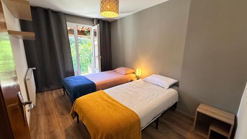 two beds in a small room with a window at Chez Aneta in Sisteron