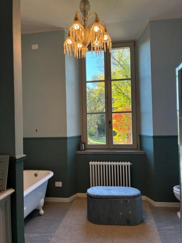 a bathroom with a chandelier and a tub and a window at MaVa' Country House in Castelnuovo Bocca dʼAdda