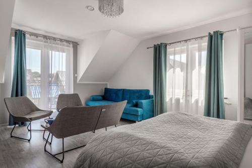 a bedroom with a bed and chairs and a blue couch at Pokoje Oaza Spokoju in Nowęcin