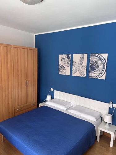 a blue bedroom with a bed with a blue wall at Appartamento Ares in Misano Adriatico