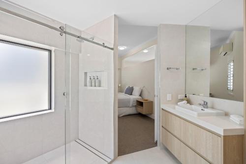 a bathroom with a shower and a sink and a bed at Mirra Chana Beachfront Apartments Mooloolaba in Mooloolaba