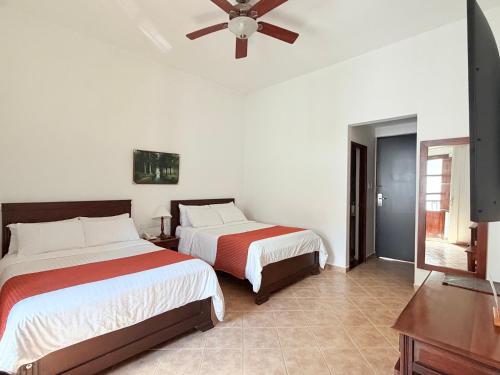 a bedroom with two beds and a ceiling fan at Hotel La Plazuela in Popayan