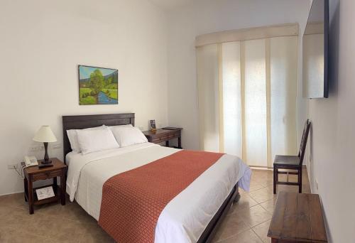 a bedroom with a bed and a table and a chair at Hotel La Plazuela in Popayan