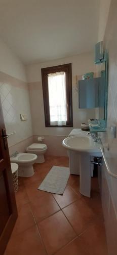 a bathroom with two sinks and a toilet and a window at Casa Signorile in Villasimius