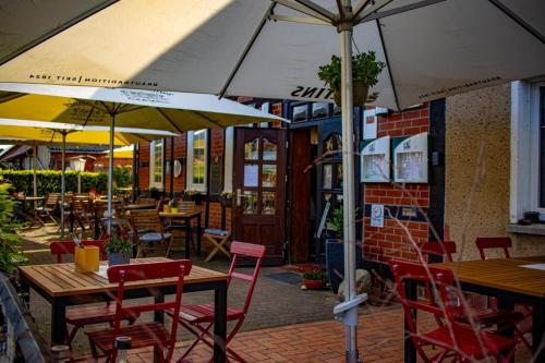 ein Restaurant mit Tischen, Stühlen und einem Sonnenschirm in der Unterkunft Restaurant und Pension Zur Wildgans in Arendsee
