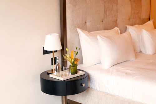 a bed with a side table with a lamp and flowers at Suites By Le Rêve in Tangier
