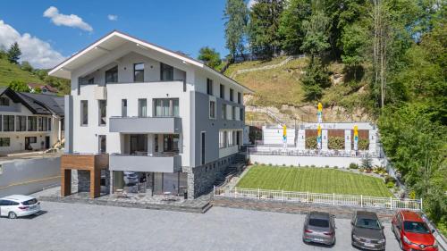 ein weißes Haus mit auf einem Parkplatz abgestellten Autos in der Unterkunft Vila Core in Rucăr
