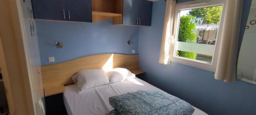 a blue bedroom with a bed with a window at vent de liberté 80 camping les peupliers in Vironchaux