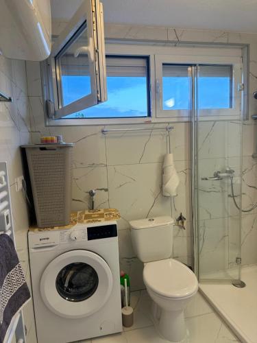 a bathroom with a washing machine and a toilet at Irma Haus in Jadranovo