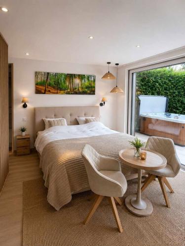 a bedroom with a large bed and a table and chairs at Le Cocon, Jacuzzi privé Spa Francorchamps in Spa