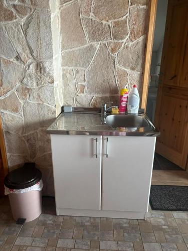 a bathroom with a sink and a stone wall at Apartman Lucija in Žabljak