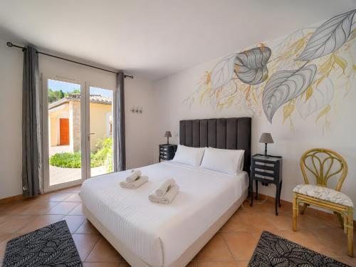 a bedroom with a large white bed and a chair at La Bastide au Soleil in Flayosc