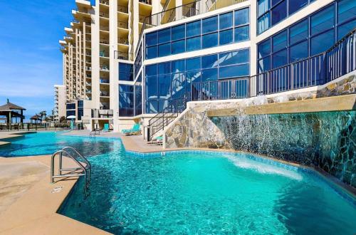 a swimming pool with a waterfall in front of a building at Beachfront Paradise at Phoenix II 2046 in Orange Beach