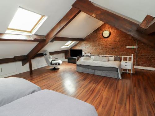 a bedroom with two beds and a brick wall at Sugar Loft in Wigton