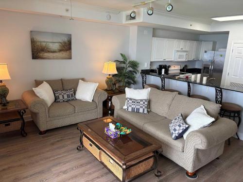 a living room with two couches and a kitchen at Oceanfront Condo with Shared Pool Hot Tub & Gym in Panama City Beach