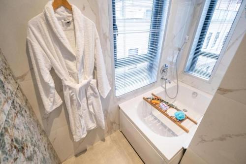 a white robe hanging on a wall next to a bath tub at Platine Plus Suite in Istanbul