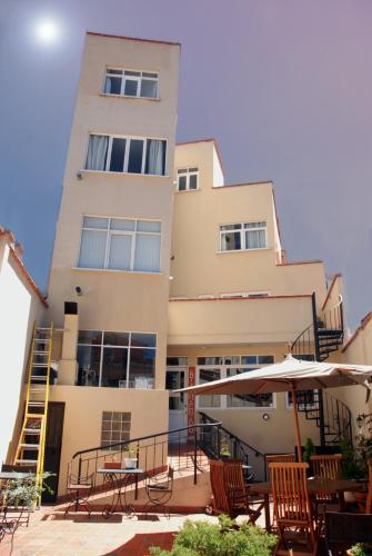 a building with chairs and an umbrella in front of it at Rendezvous Hostal in La Paz