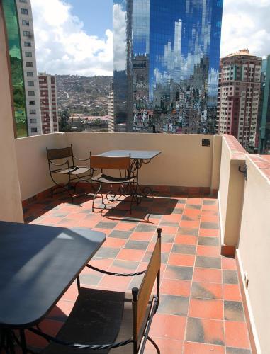 a balcony with tables and chairs and a view of a city at Rendezvous Hostal in La Paz