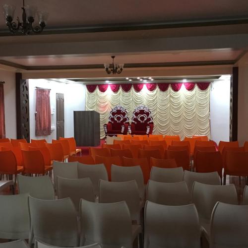 an empty auditorium with orange chairs and a stage at Sun Shine in Chennai