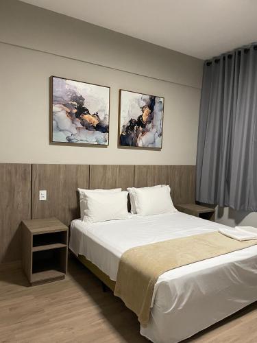 a bedroom with a bed and three paintings on the wall at Serra Palace Hotel in Ouro Branco